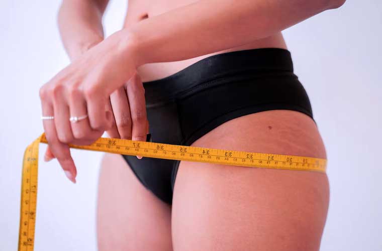 femme avec un mètre en train de mesurer son tour de cuisses