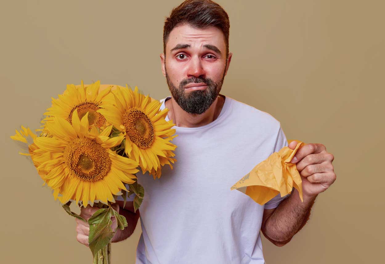 homme avec le nez qui coule tenant des tournesols dans ses mains