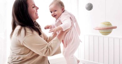 maman portant son bébé par dessus une barrière