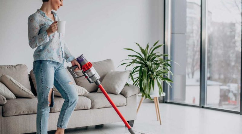 femme en train de passer l'aspirateur dans le salon