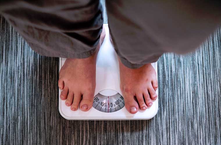 personne en train de se peser sur une balance