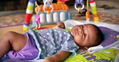 bébé allongé sur un tapis d'éveil avec un portique d'activité
