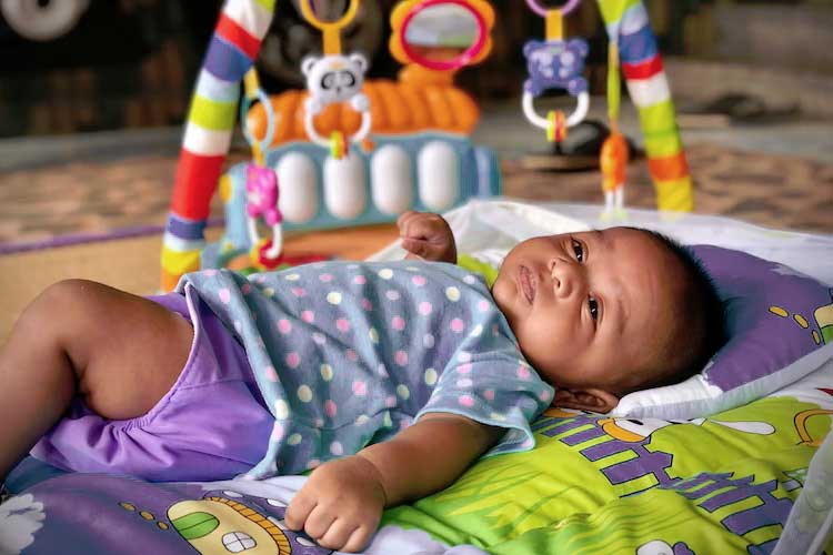 bébé allongé sur un tapis de jeu avec un portique d'activité
