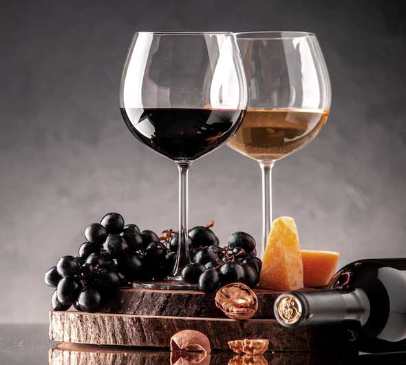 verres à vin, raisins frais, noix, fromage sur une planche de bois